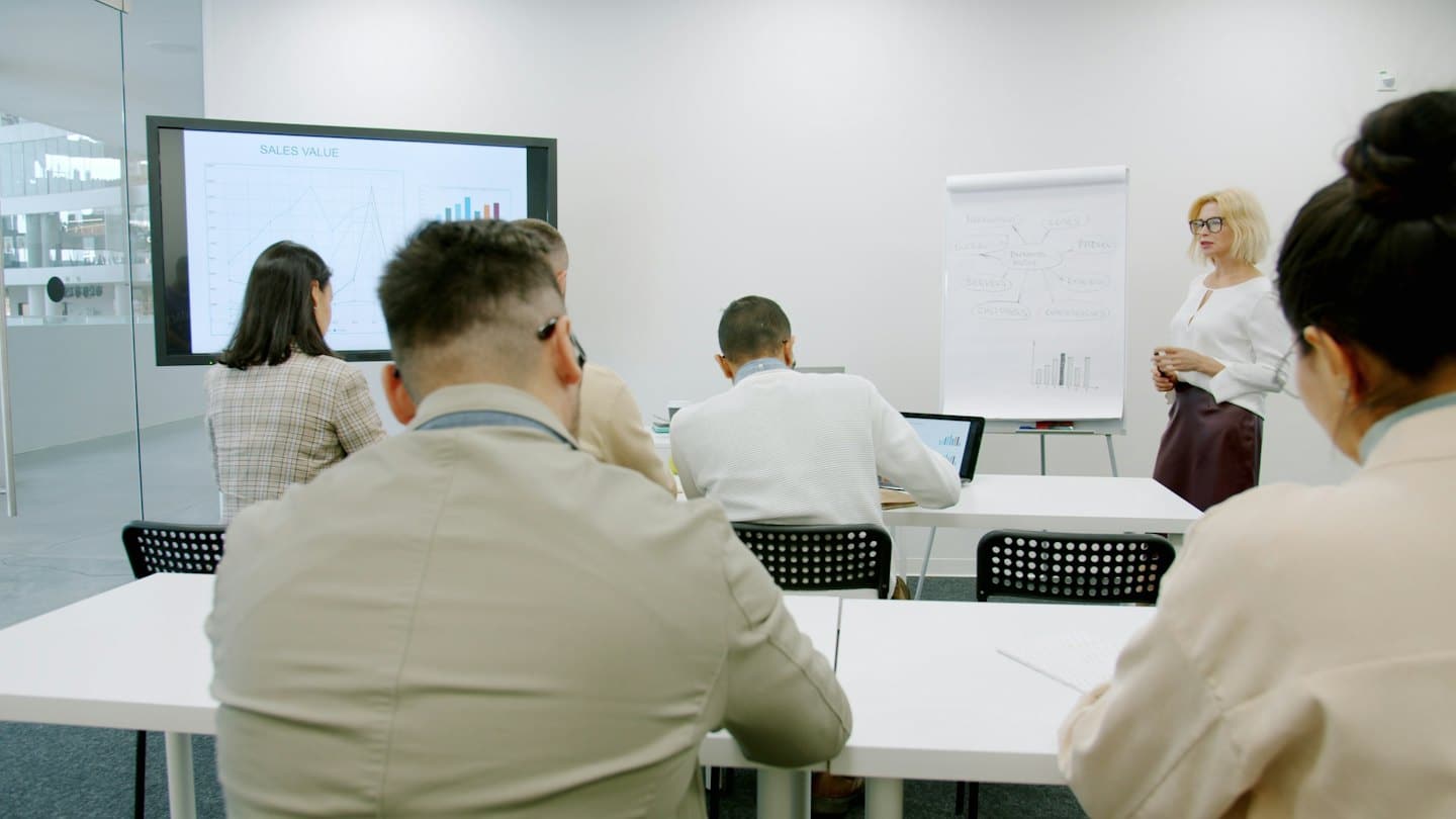 Woman presents sales data on a screen to an audience.